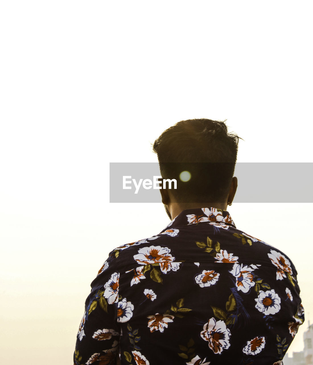 REAR VIEW OF MAN STANDING AGAINST SKY