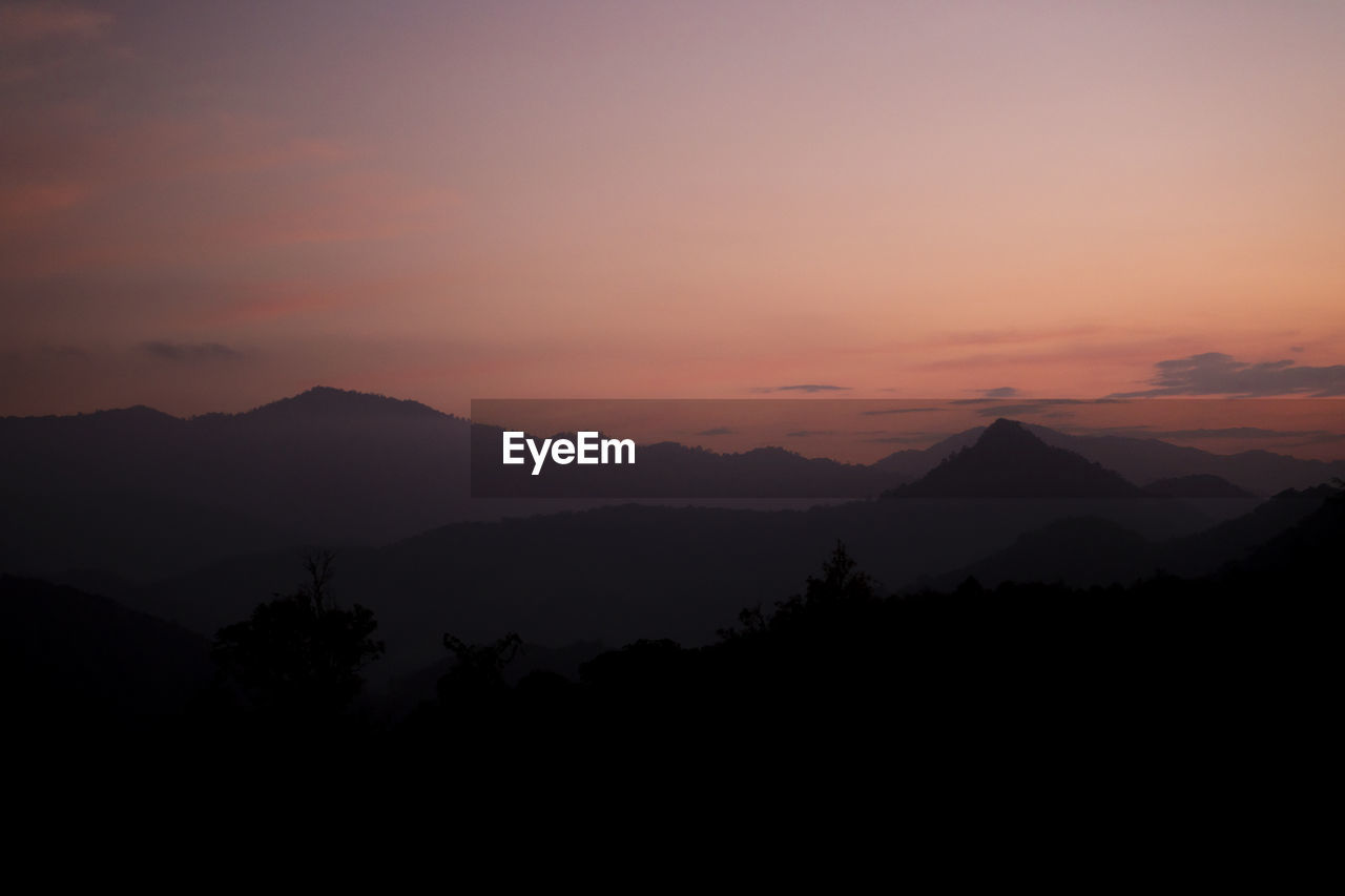 Scenic view of silhouette mountains against orange sky