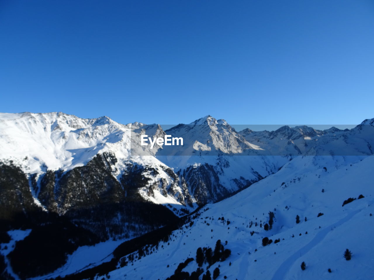 Scenic view of snowcapped mountains against clear blue sky