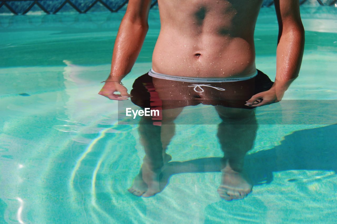 Low section of shirtless man in swimming pool