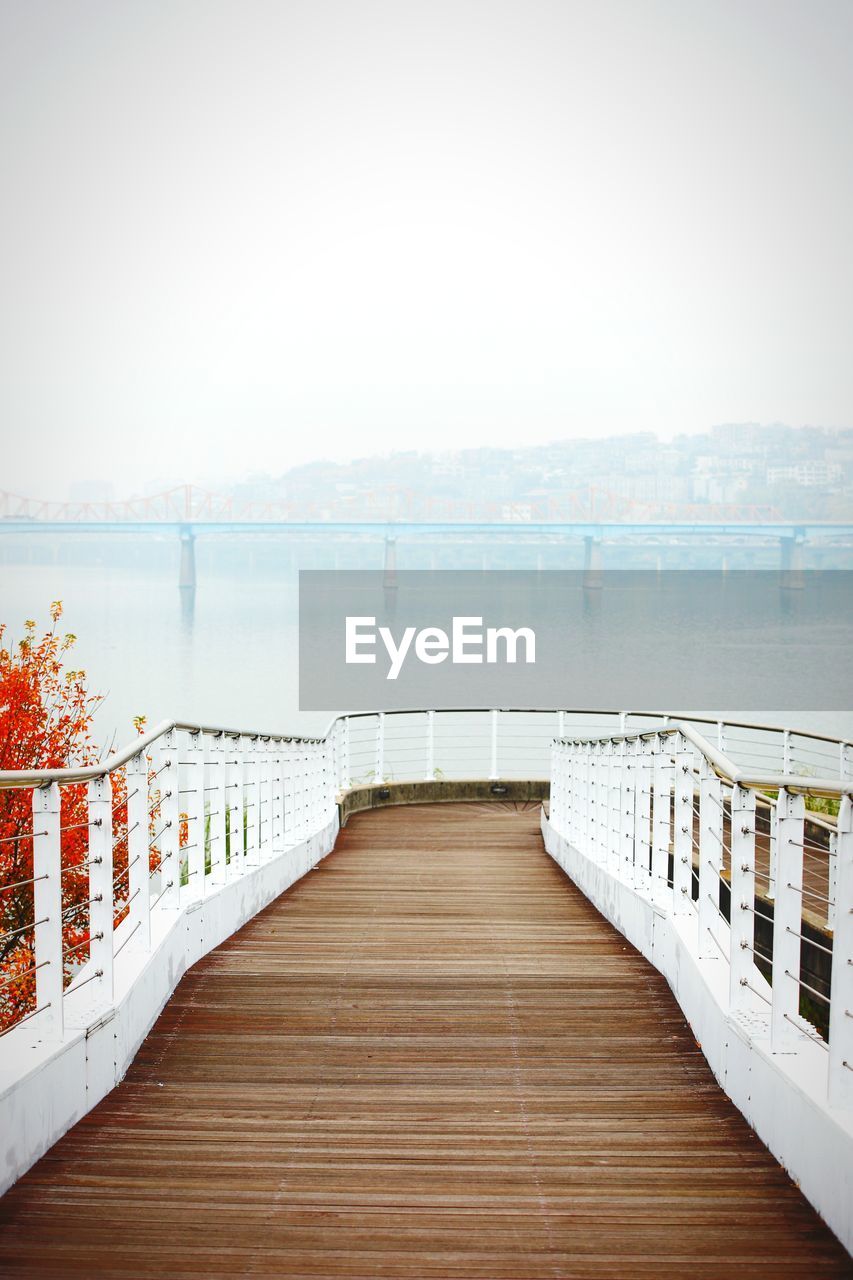 Wooden boardwalk leading towards sea against sky