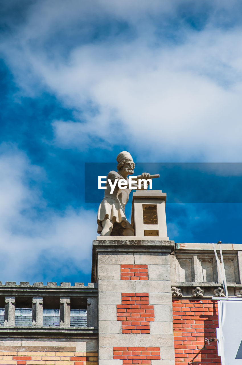 LOW ANGLE VIEW OF STATUE AGAINST BUILDING AND SKY