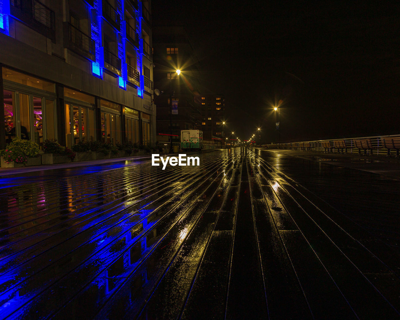 Light trails on street amidst illuminated buildings in city at night