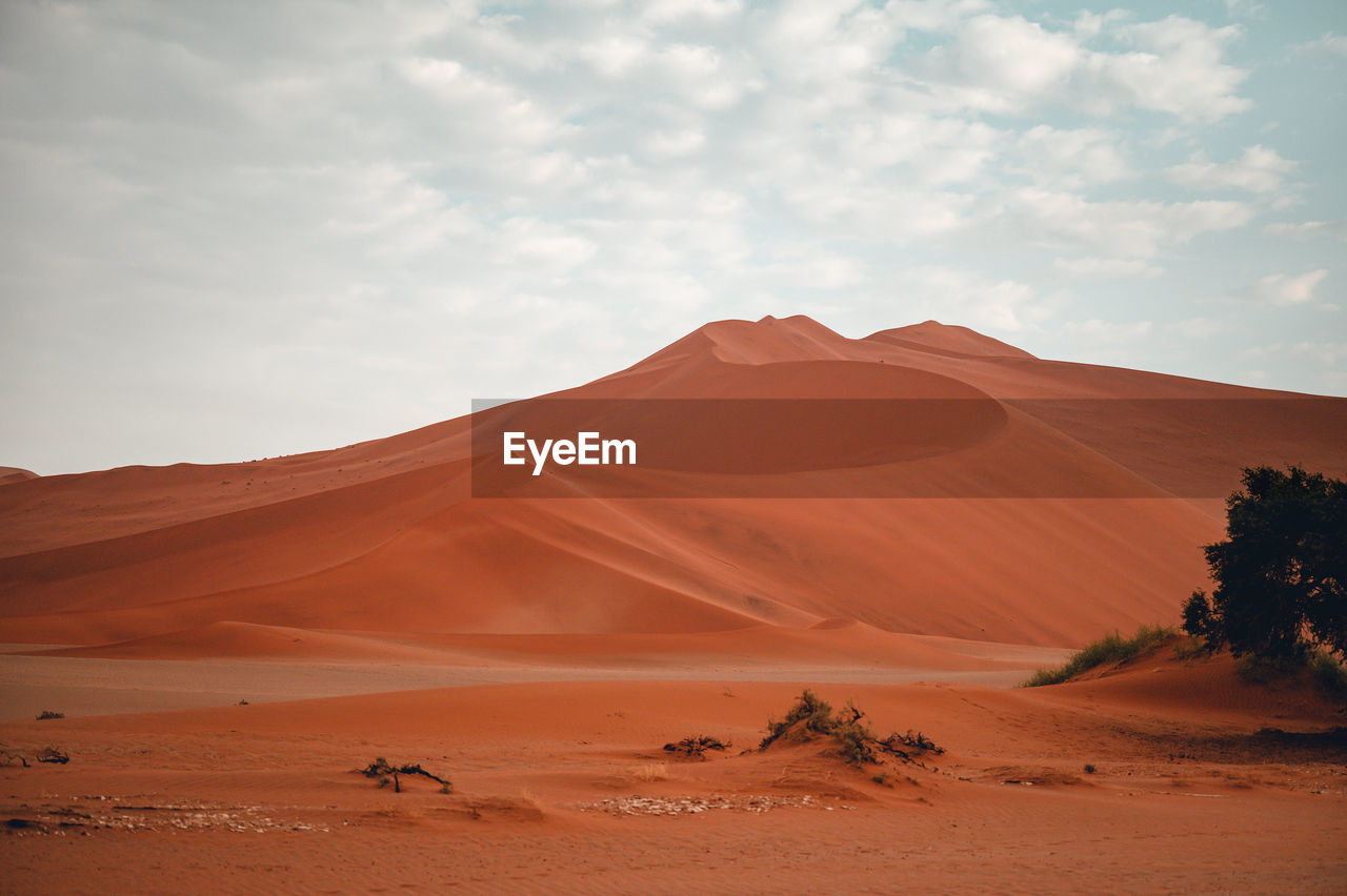 Scenic view of desert against cloudy sky