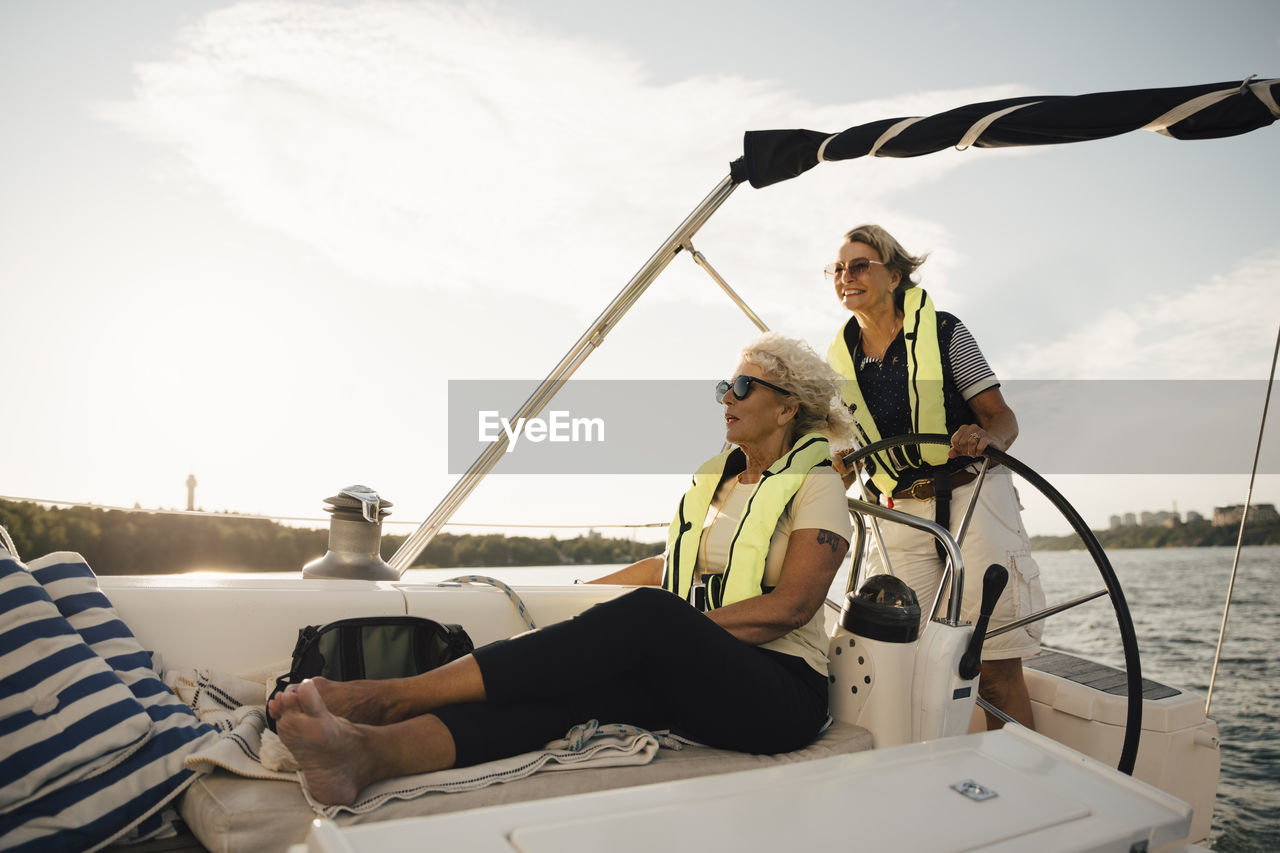 Cheerful senior female friends in boat on sunny day