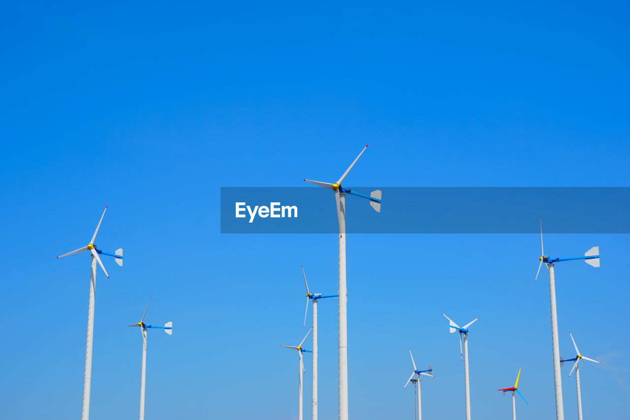 LOW ANGLE VIEW OF WINDMILLS AGAINST CLEAR BLUE SKY