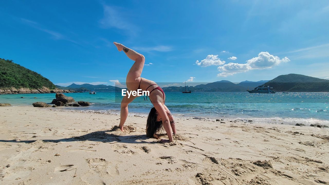 Full length of woman standing at beach against sky