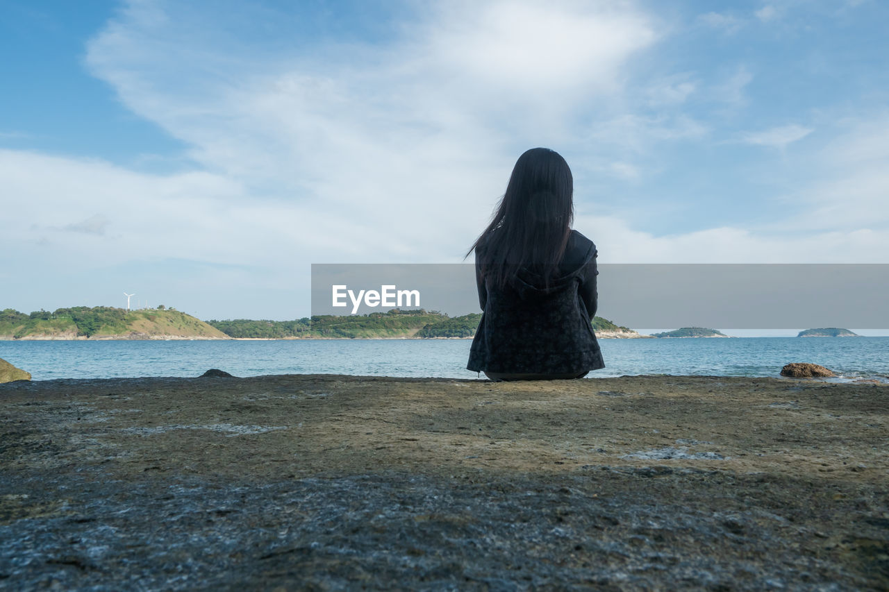 REAR VIEW OF WOMAN STANDING ON BEACH