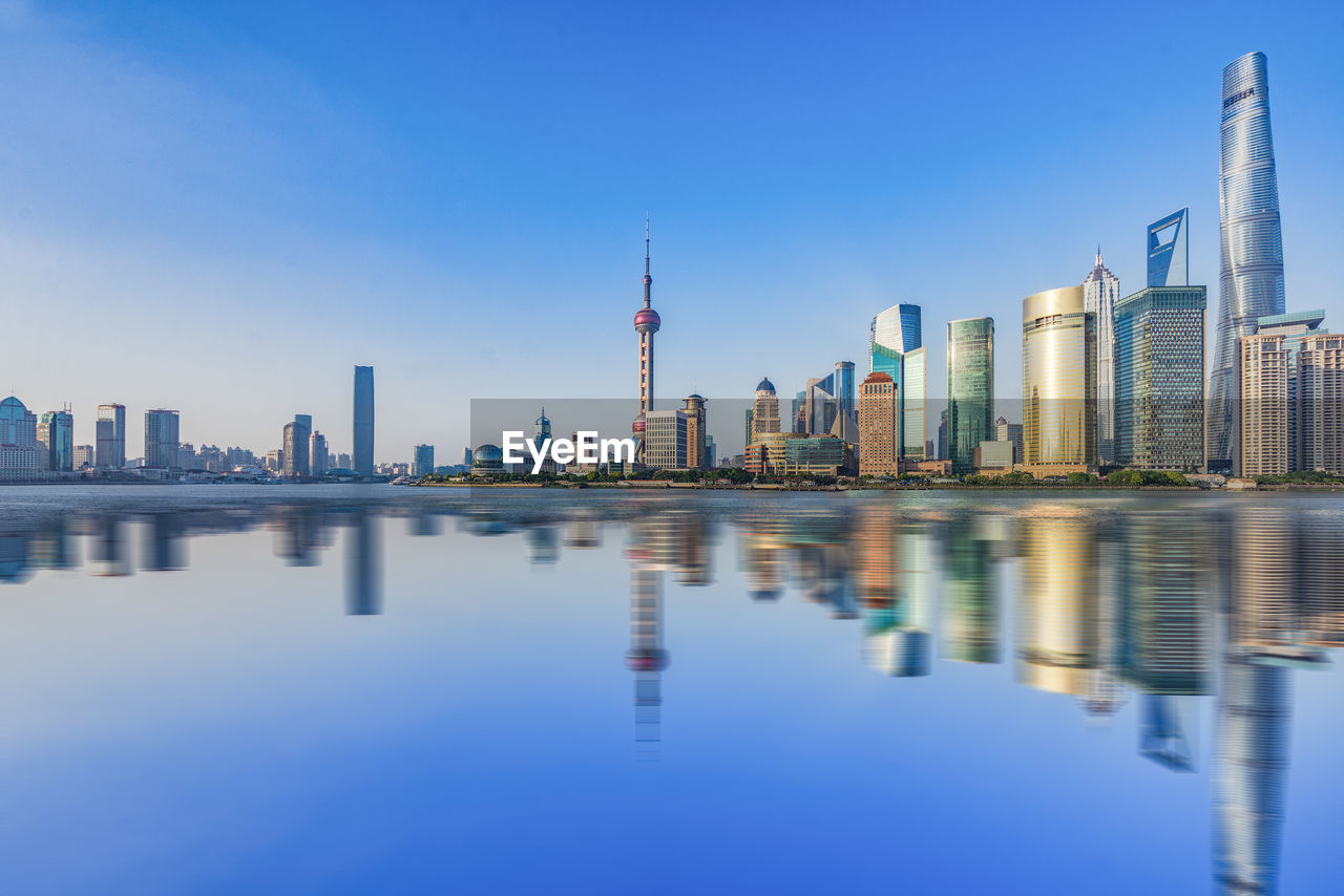 REFLECTION OF BUILDINGS IN LAKE AGAINST SKY