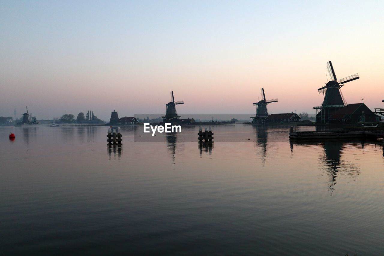 Silhouette cranes against sky at sunset