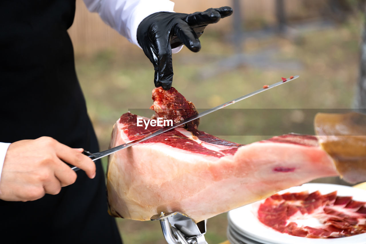 Ham cutter with gloves at a party cutting thin slices of iberian ham