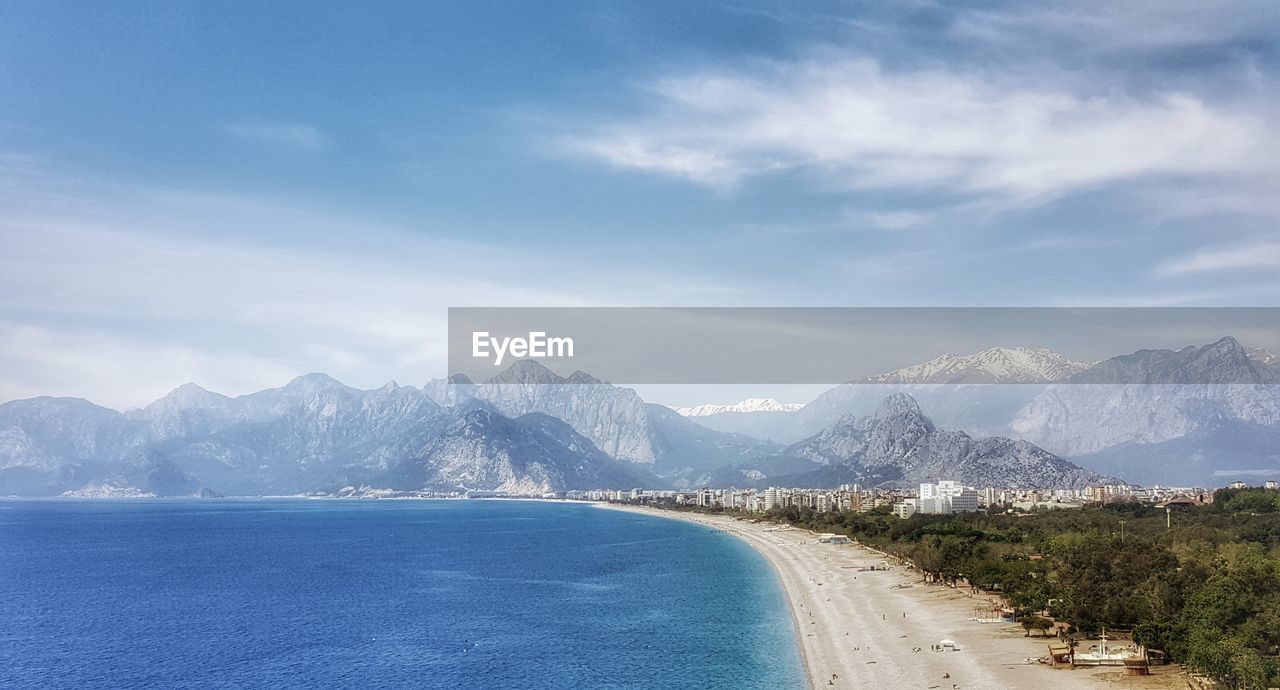 Scenic view of sea and mountains against blue sky