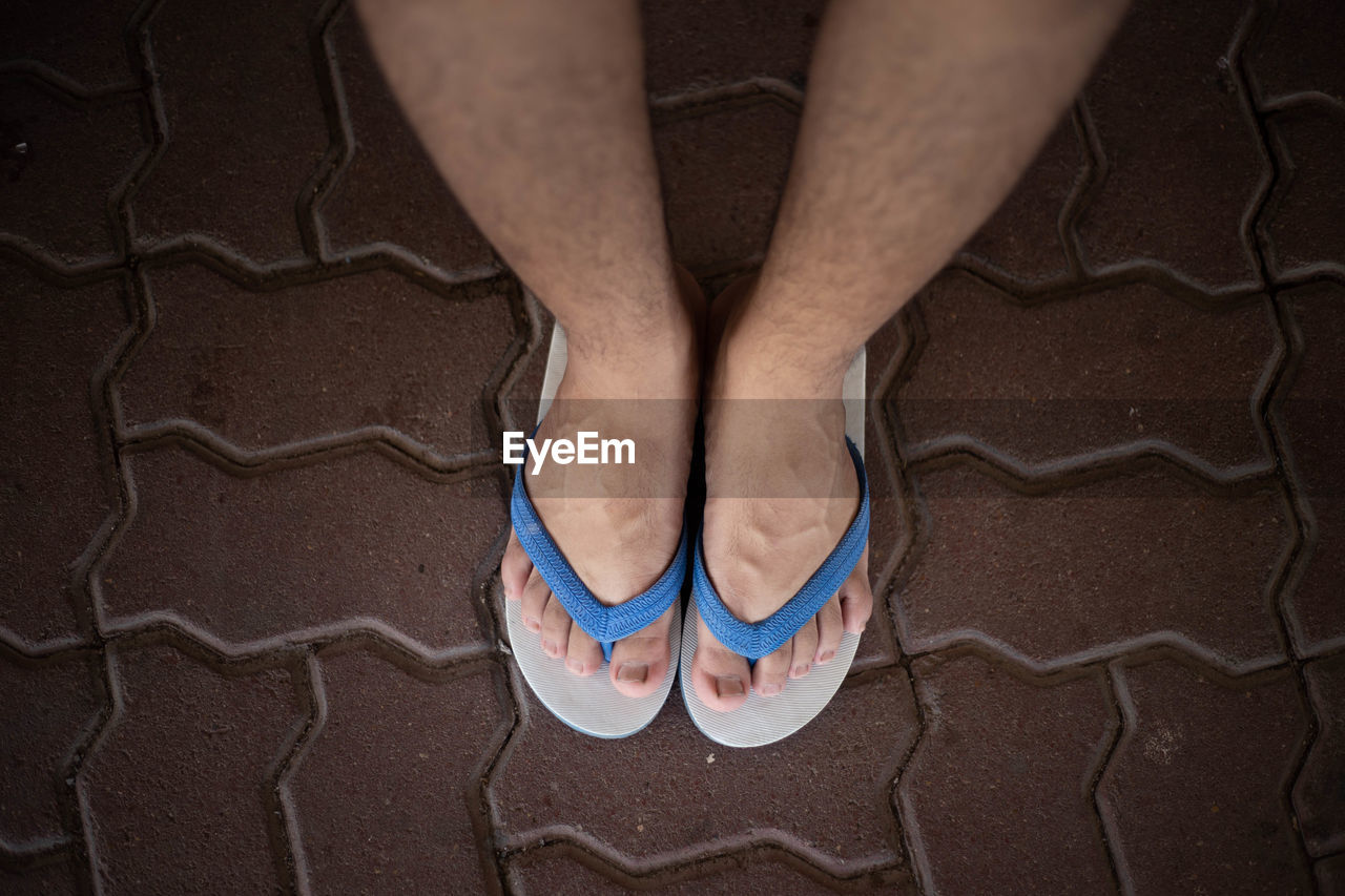 LOW SECTION OF MAN WEARING SHOES STANDING ON FOOTPATH