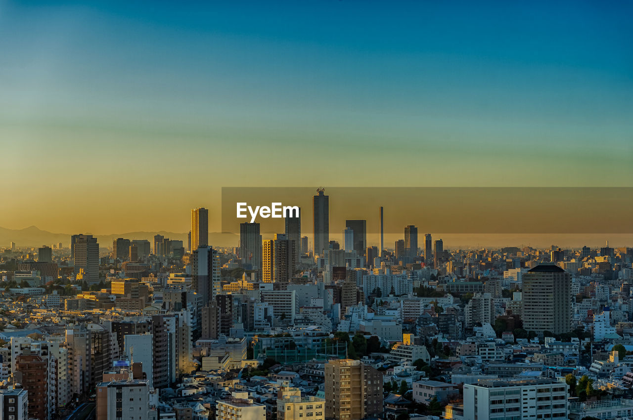 Modern buildings in city against sky during sunset