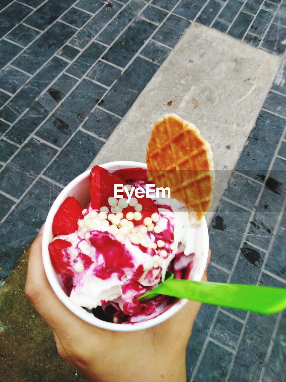 Cropped hand holding frozen yogurt on street