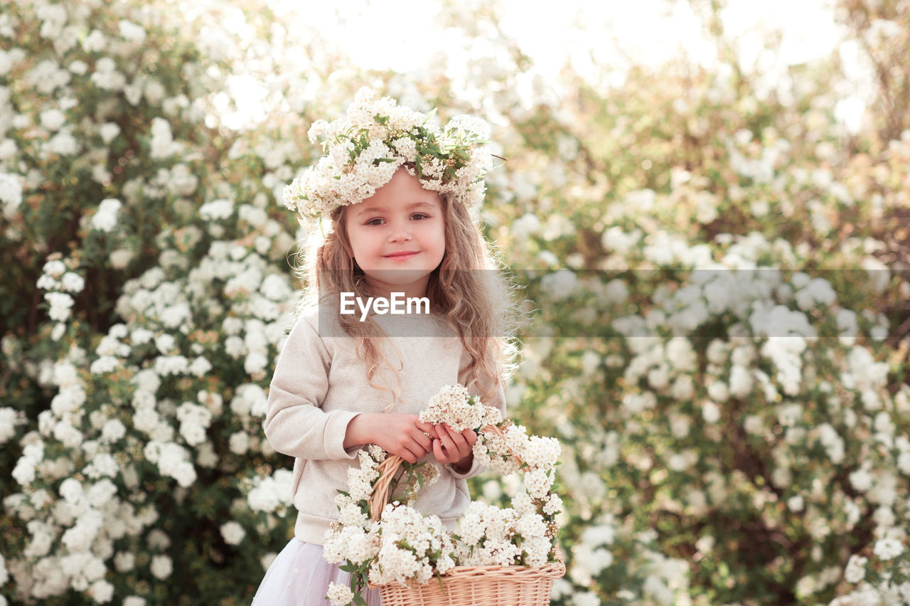 spring, plant, flower, flowering plant, one person, women, nature, bride, child, portrait, childhood, hairstyle, beauty in nature, smiling, long hair, front view, clothing, freshness, happiness, dress, female, emotion, blossom, adult, day, looking at camera, fashion, blond hair, outdoors, wreath, looking, standing, tree, innocence, lifestyles, springtime, crown, three quarter length, young adult, wedding dress, portrait photography, pink, white, person, cute, bouquet, holding, flower arrangement, leisure activity, laurel wreath, royalty, brown hair, summer, growth, celebration