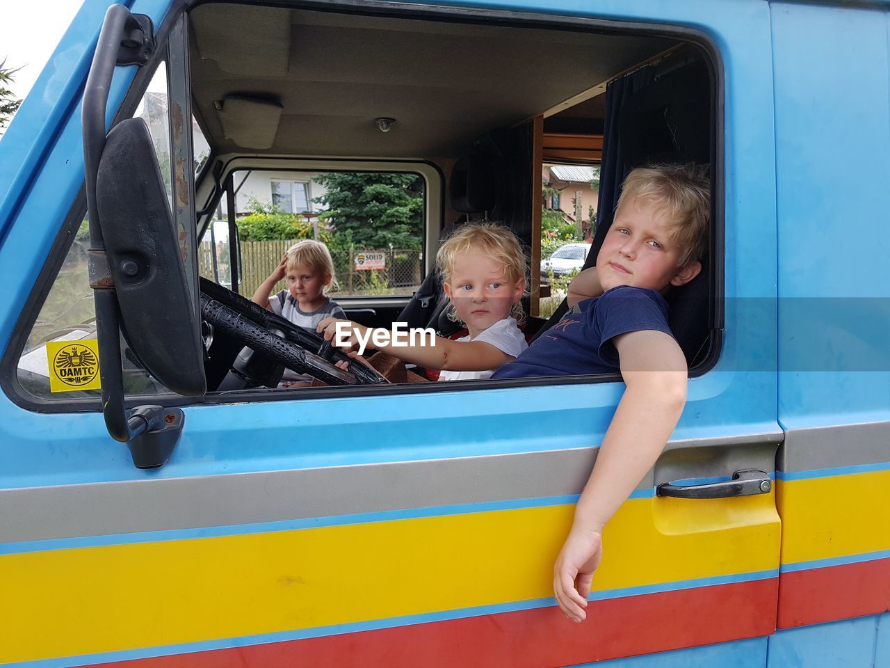 REAR VIEW OF BOYS AND PEOPLE ON CAR