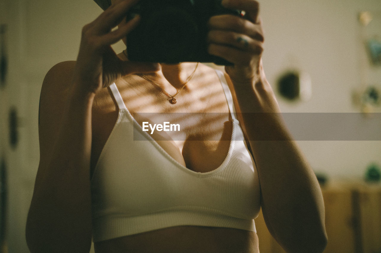 Midsection of woman in the bra in the mirror, standing at home