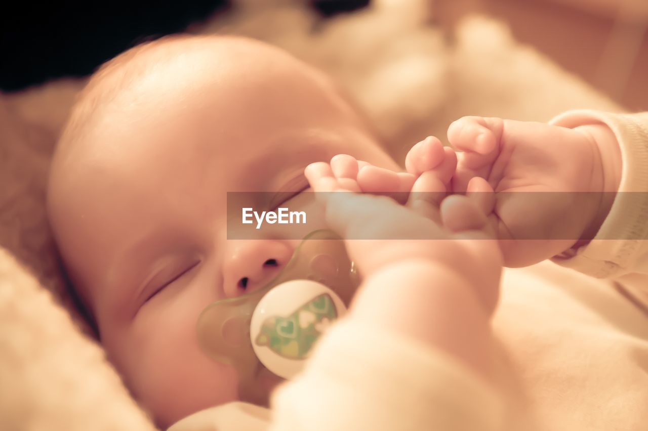 Close-up of cute baby girl sucking pacifier while sleeping at home