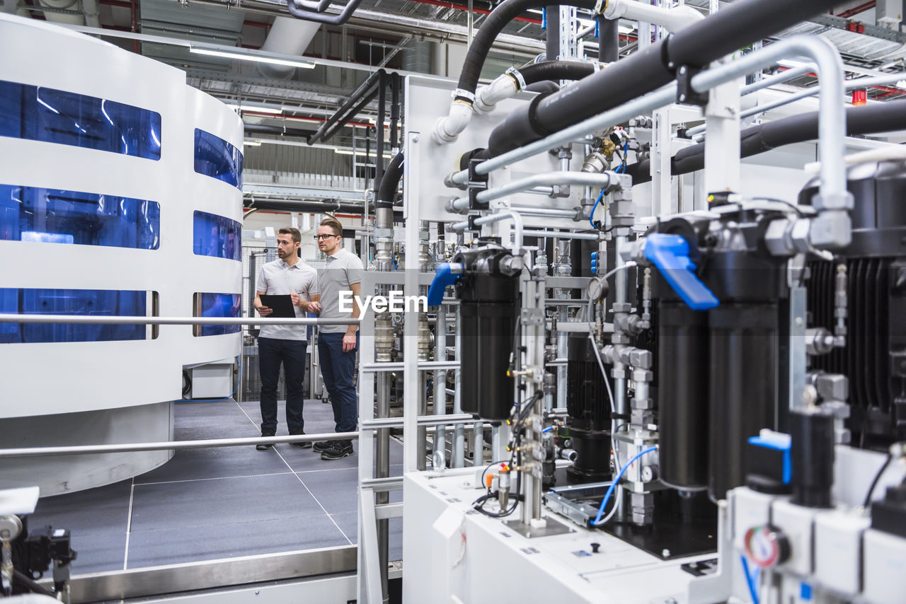 Two men looking at machine in factory shop floor