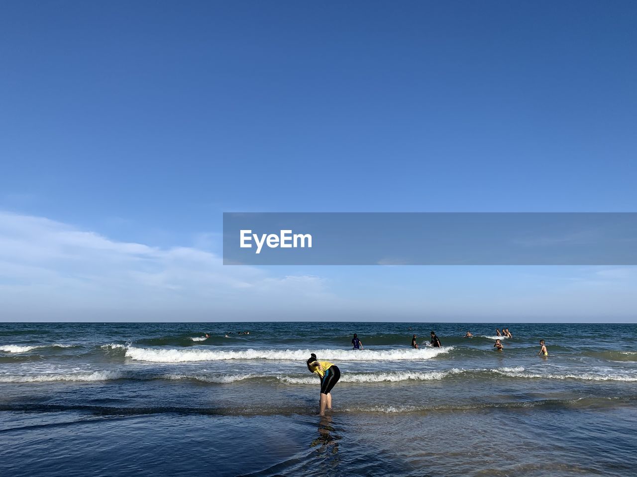 Smiling girl standing at shore against sky