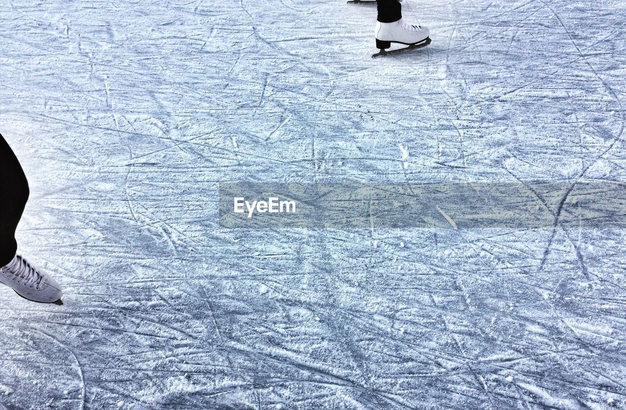 Low section of people doing ice-skating at rink