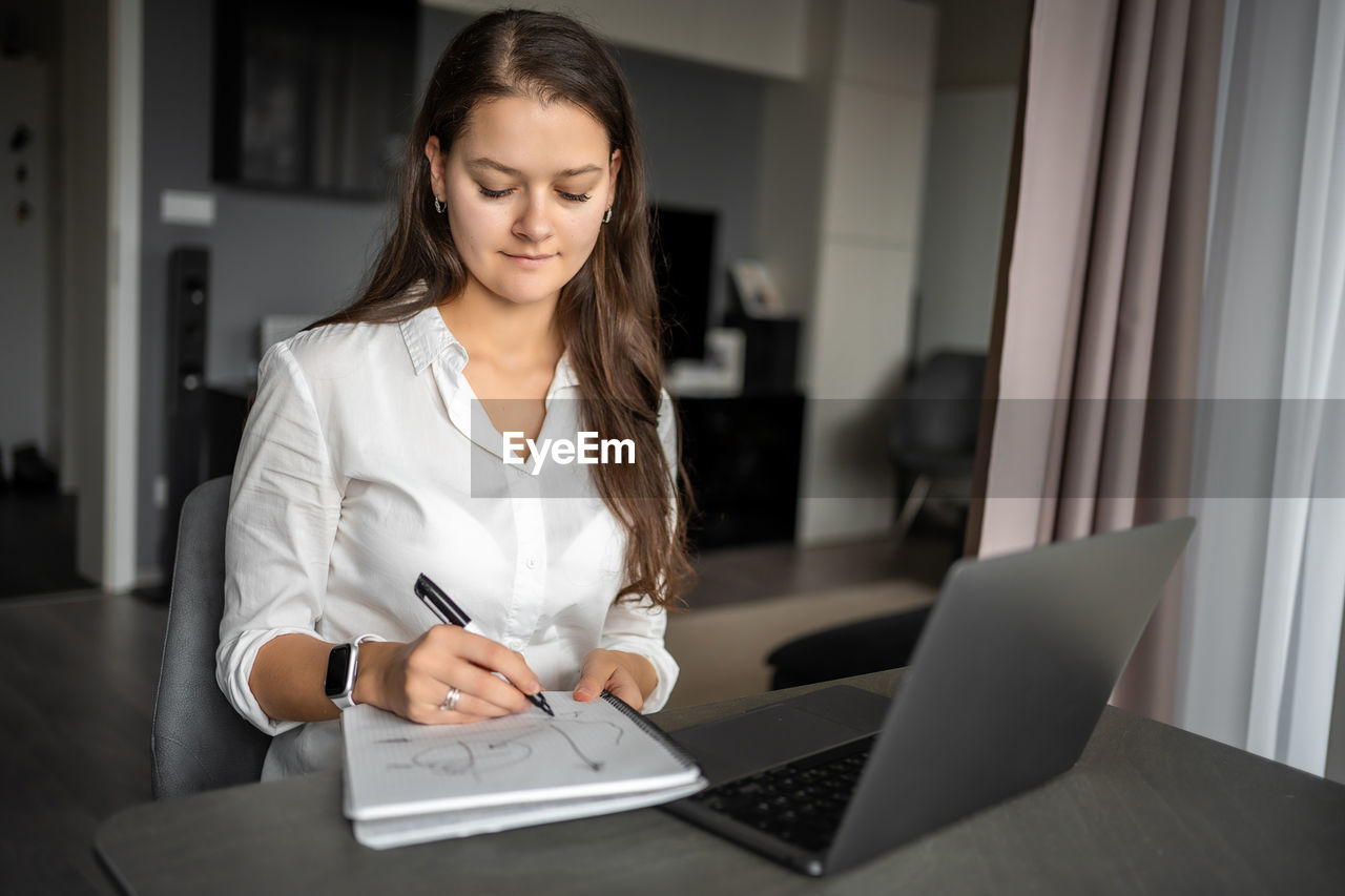 portrait of young businesswoman working at table at home