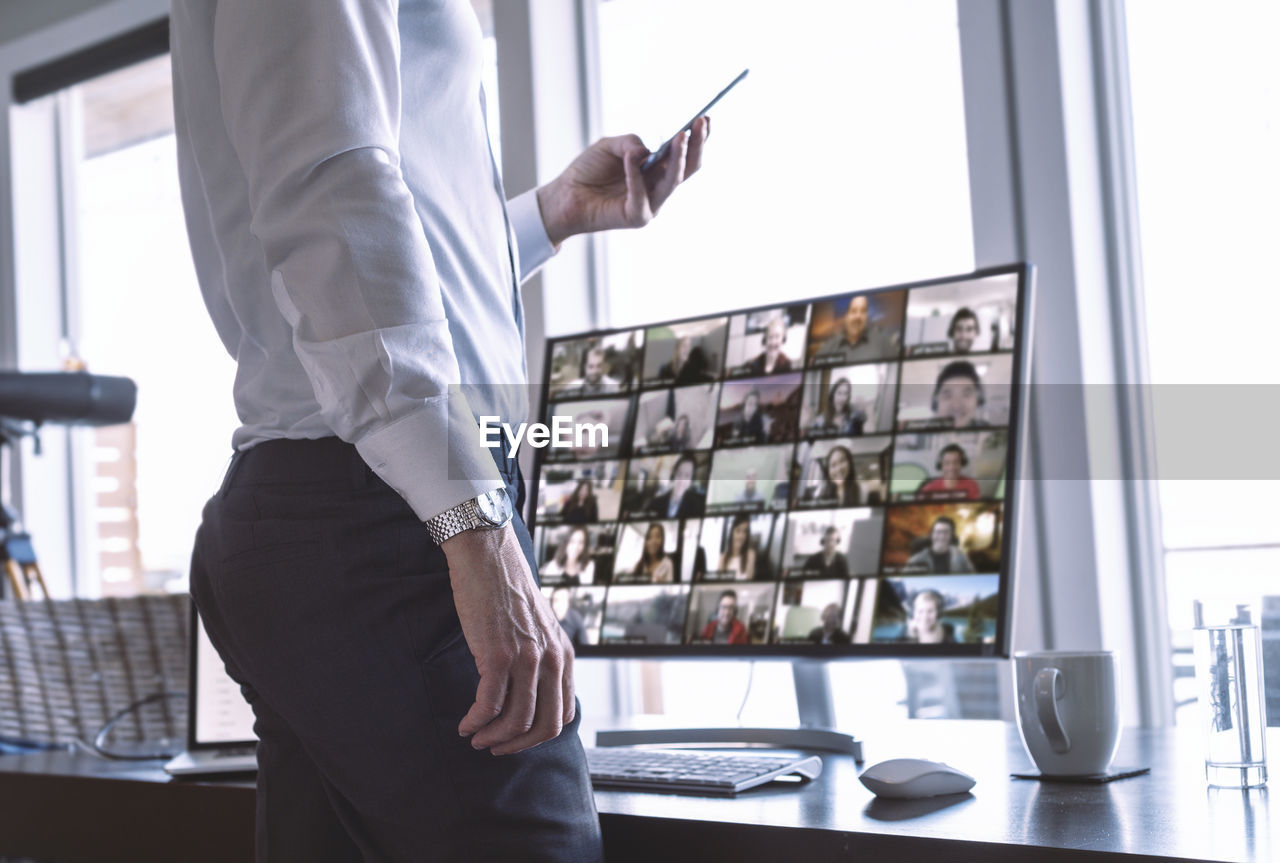 Businessman using video chat on computer and phone.