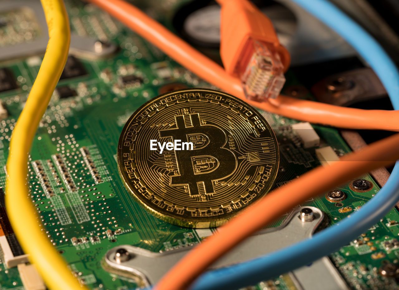 High angle view of coins amidst wires on circuit board