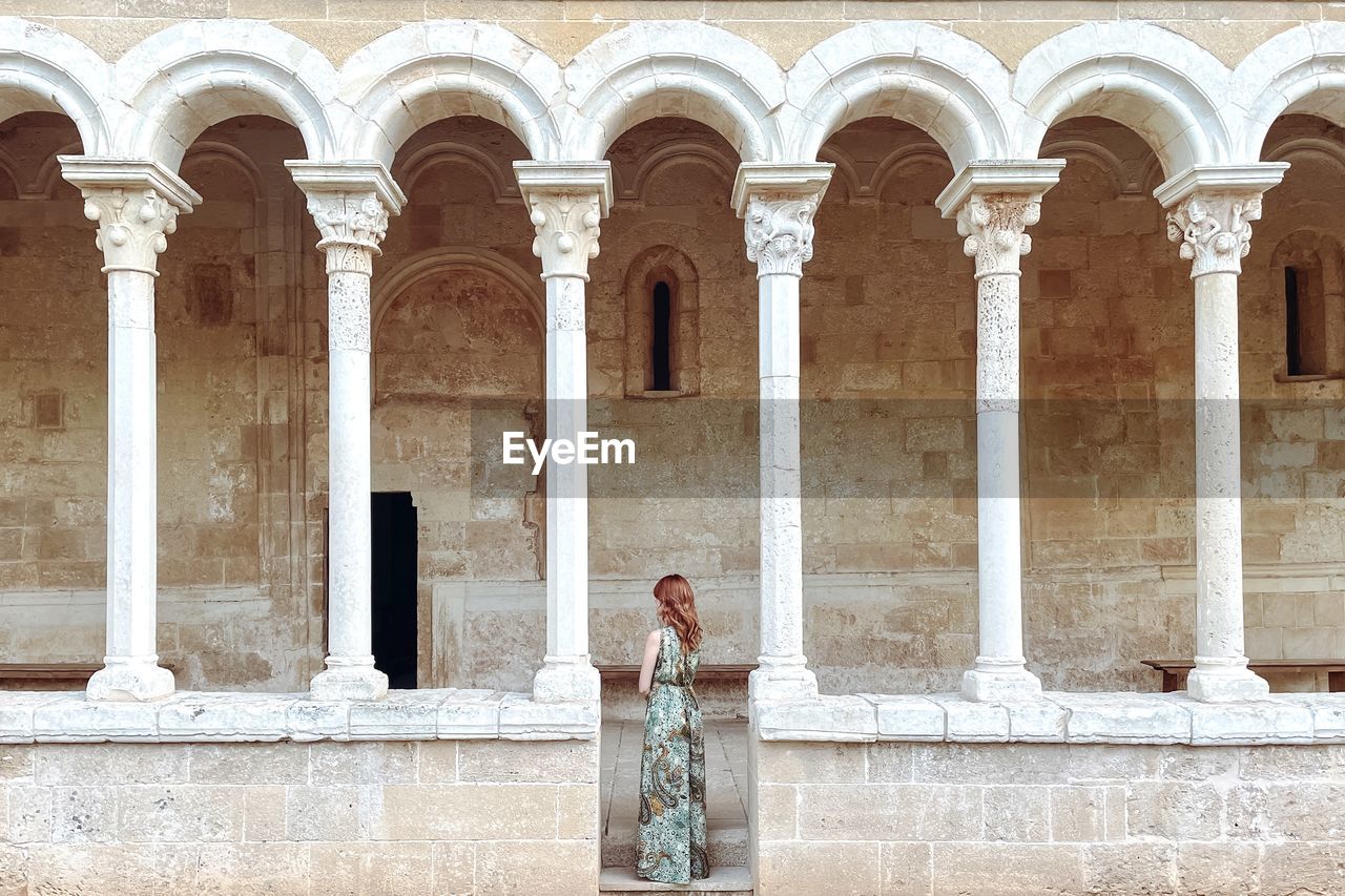 Rear view of woman standing against historic building