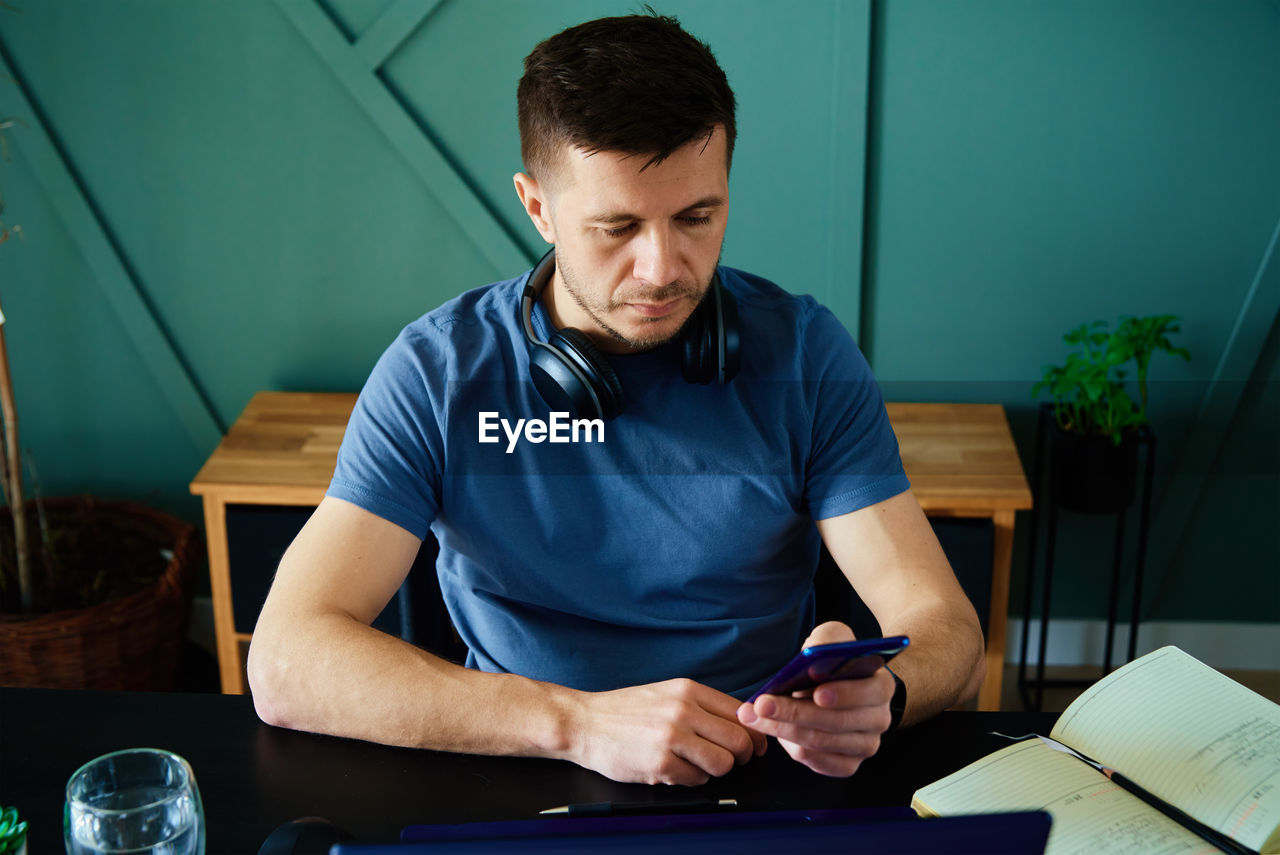 Bored man playing smartphone while working at home office