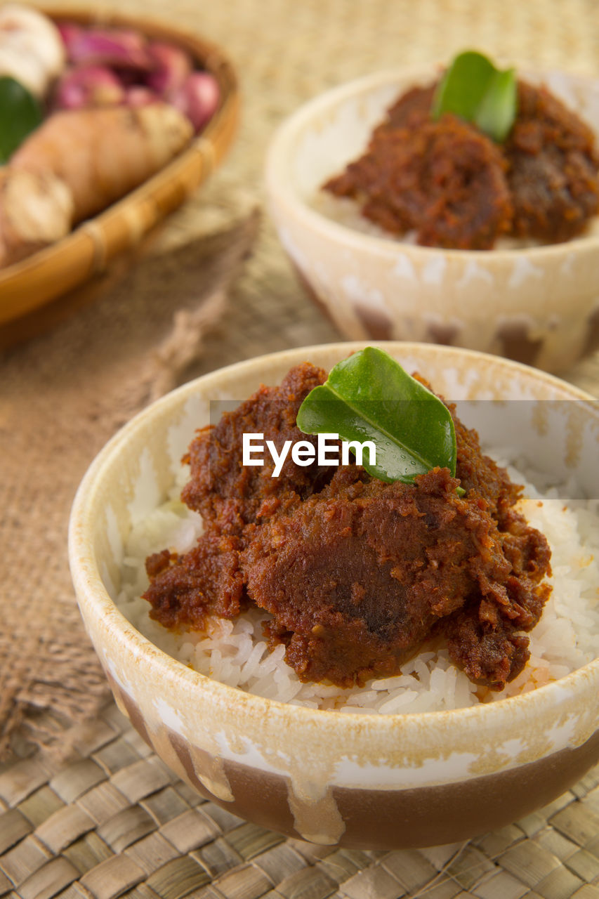 Bowl of steamed rice topped with spicy chutney on wicker mat