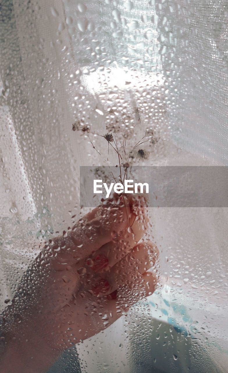 Close-up of woman seen through wet glass window
