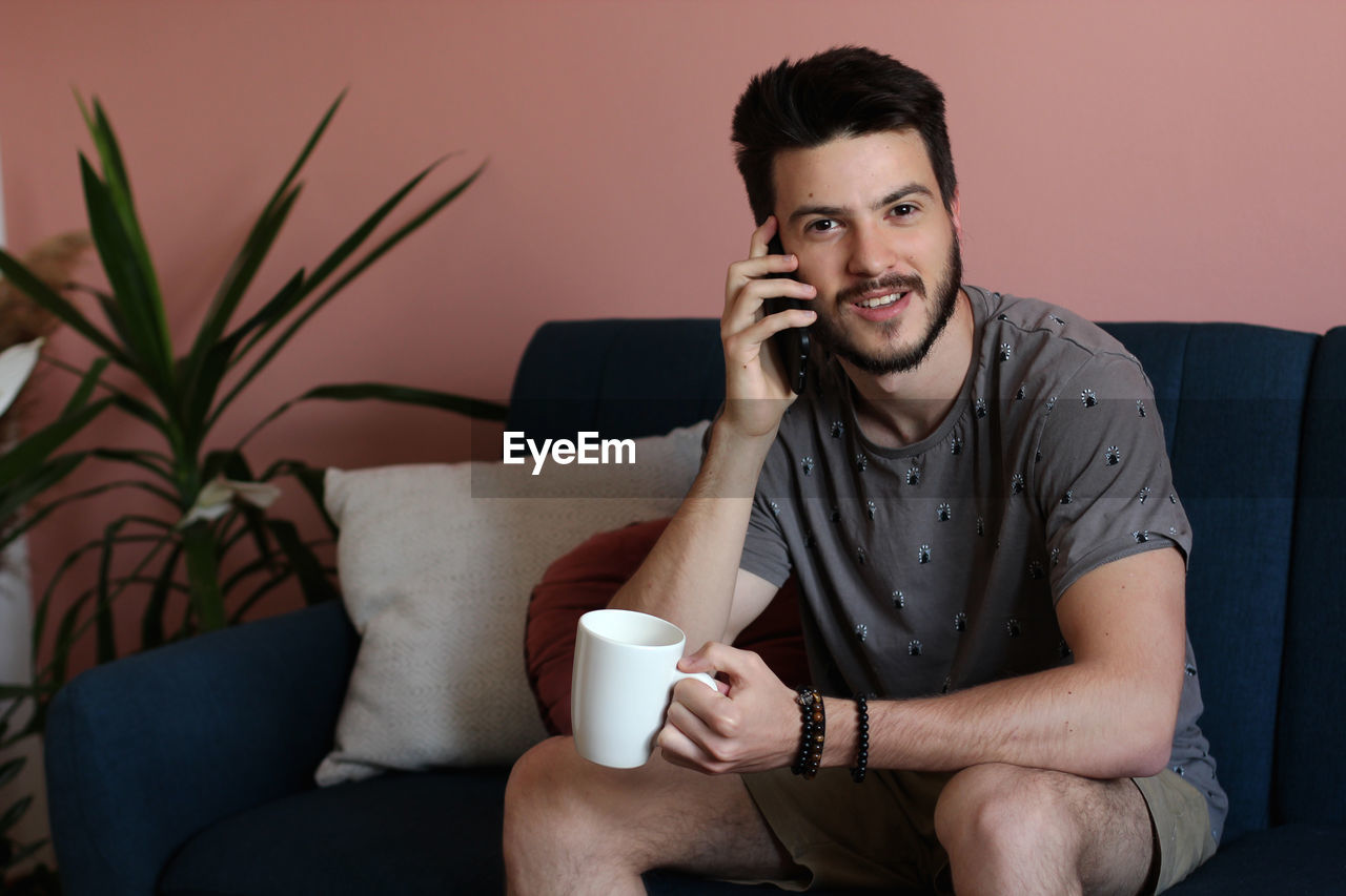 Man talking on phone while sitting in living room at home