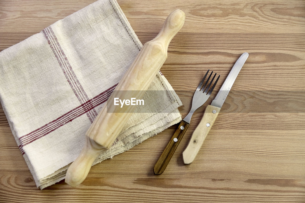 Directly above shot of tablecloth and rolling pin with fork and table knife on table