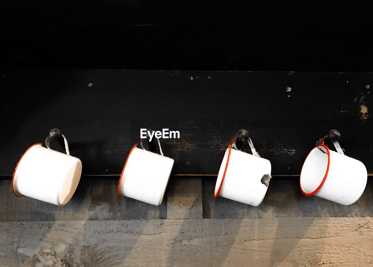 Low angle view of mugs hanging on wood