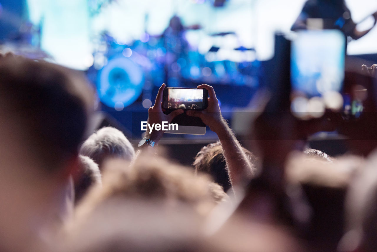 Cropped hand of man photographing in music concert