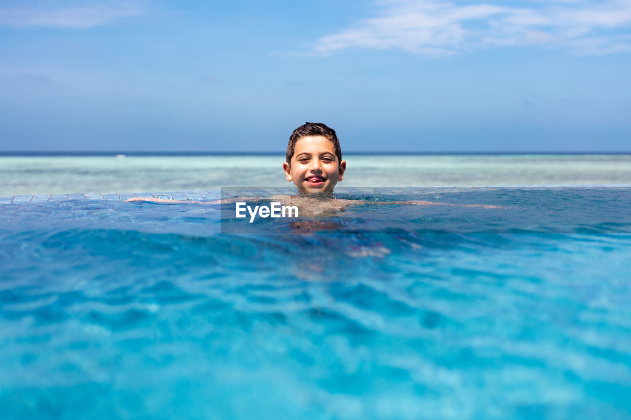 Little kid in a infinity pool near the ocean