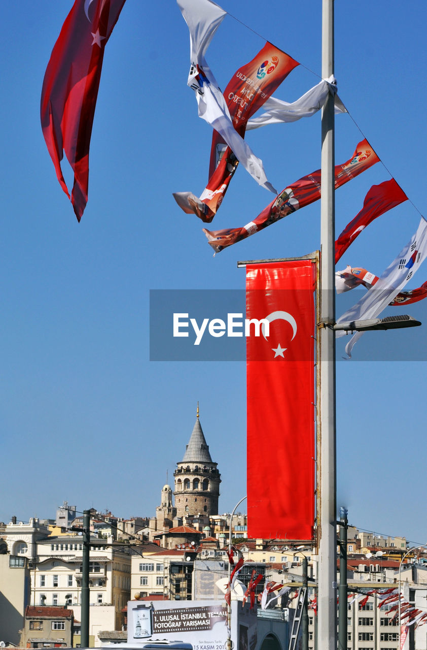 Low angle view of red flag against clear blue sky