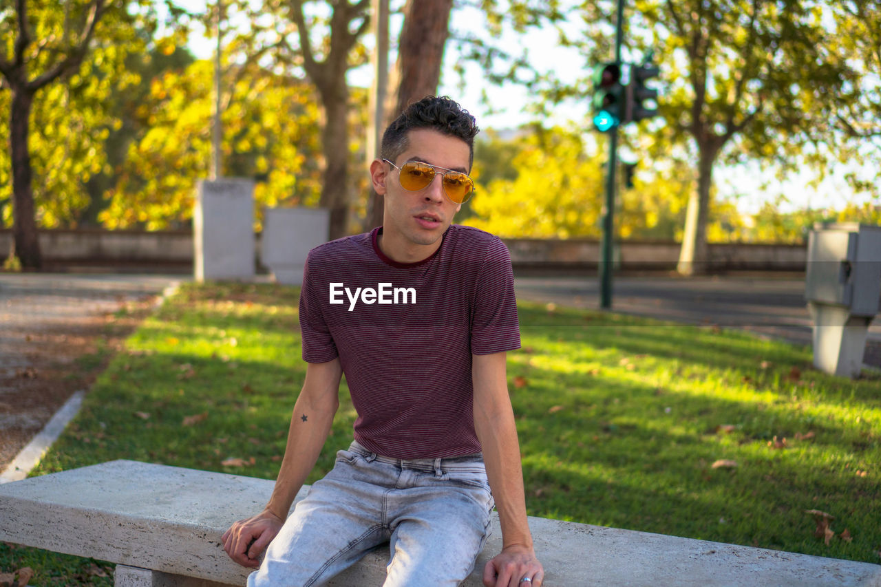 FULL LENGTH OF YOUNG MAN SITTING ON TREE