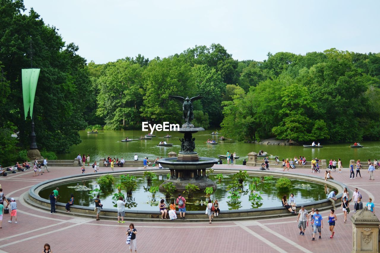 People standing around in park next to lake