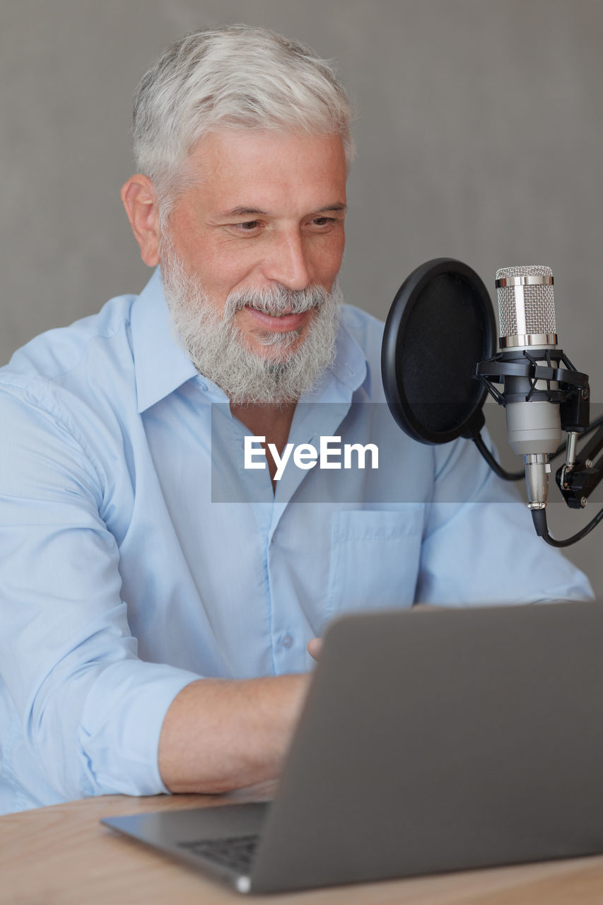 portrait of senior man using laptop while sitting on table