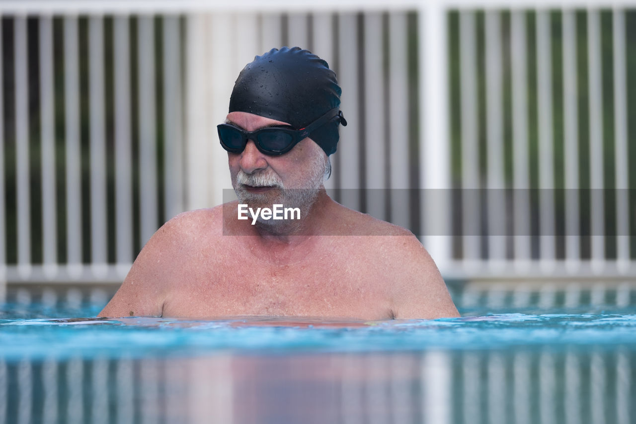 Portrait of senior man wearing sunglasses at swimming pool