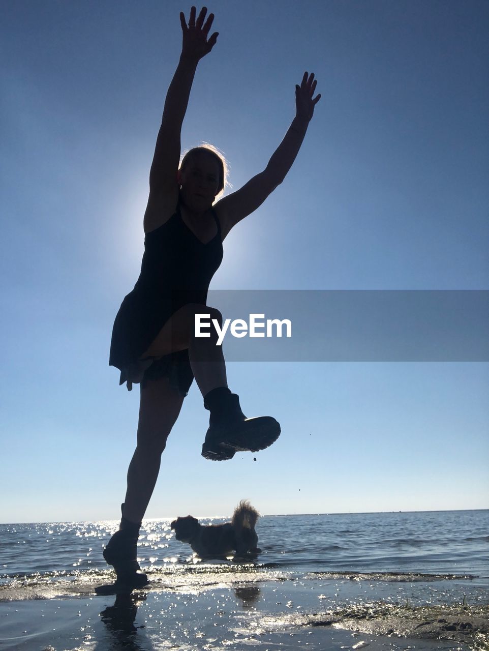 MAN JUMPING AT BEACH AGAINST SKY