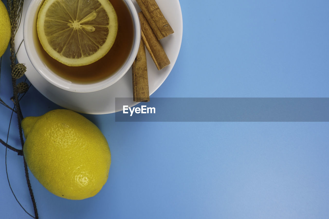 Tea and lemon in a white cup over blue background. copyspace concept.