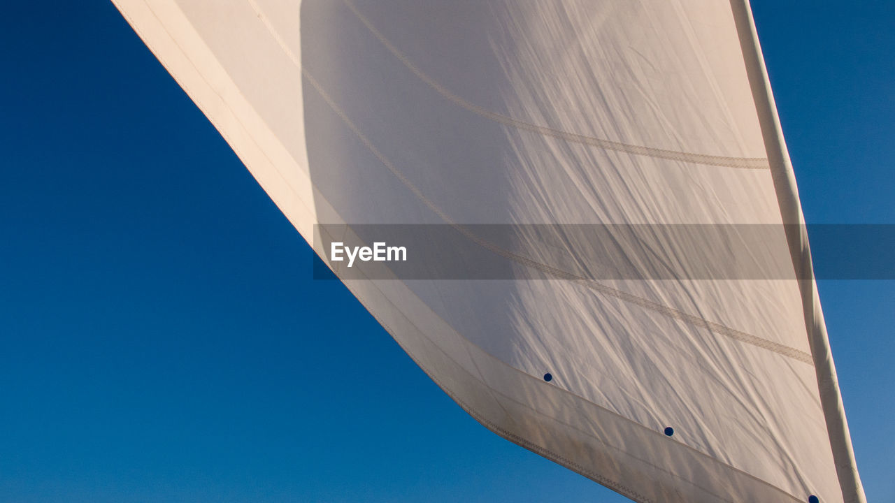 Low angle view of boat canvas against clear blue sky