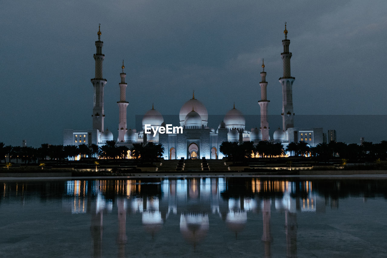 Reflection of illuminated mosque in lake at night