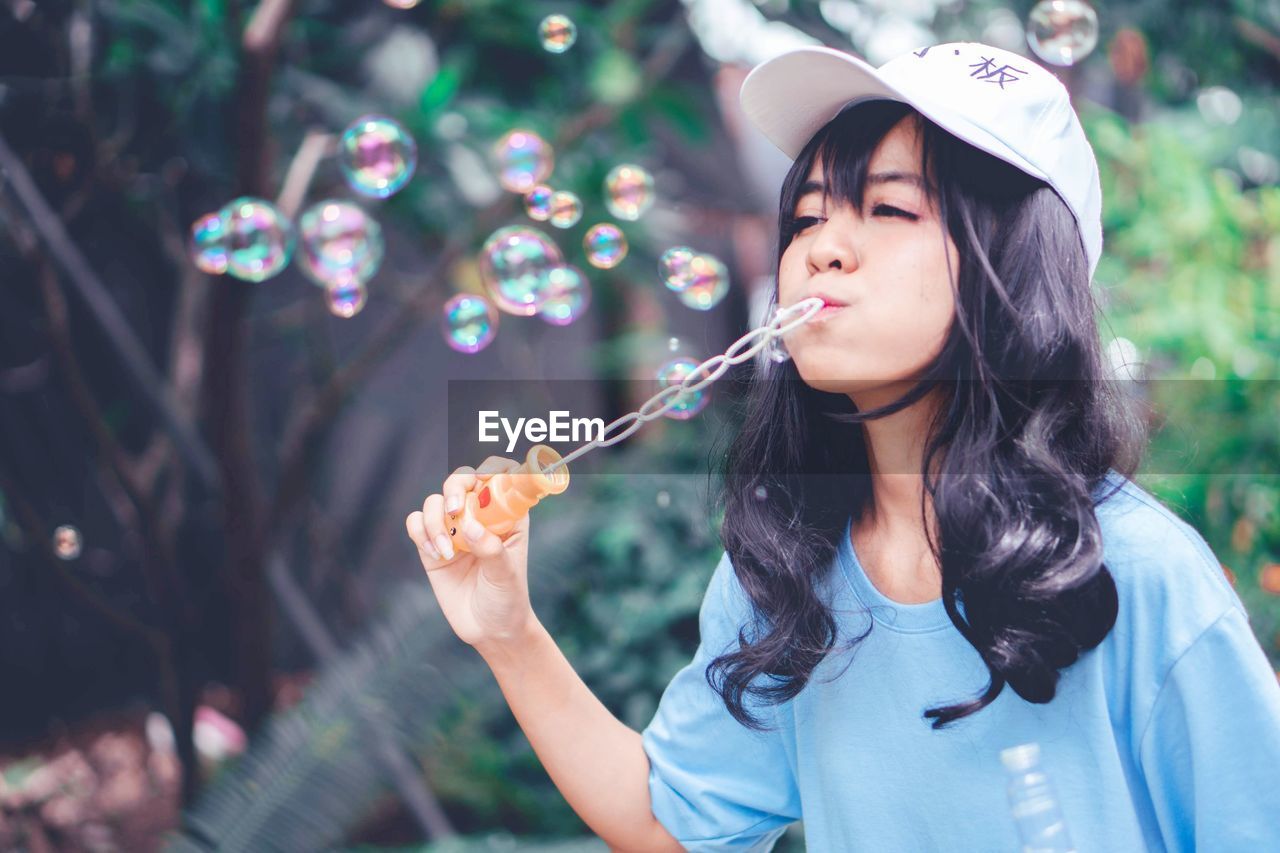 PORTRAIT OF WOMAN WITH BUBBLES IN PARK