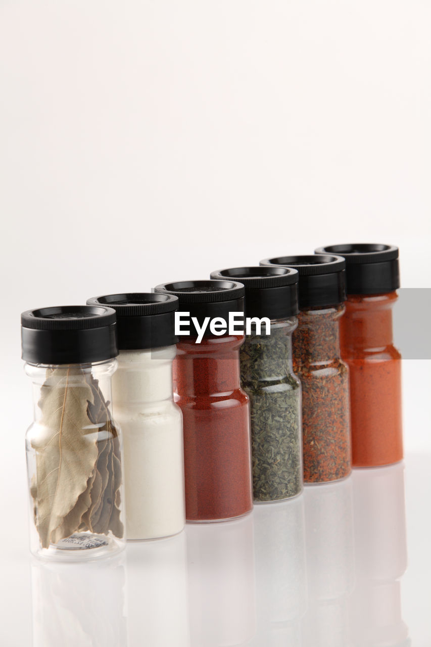 Close-up of spices in bottles against white background
