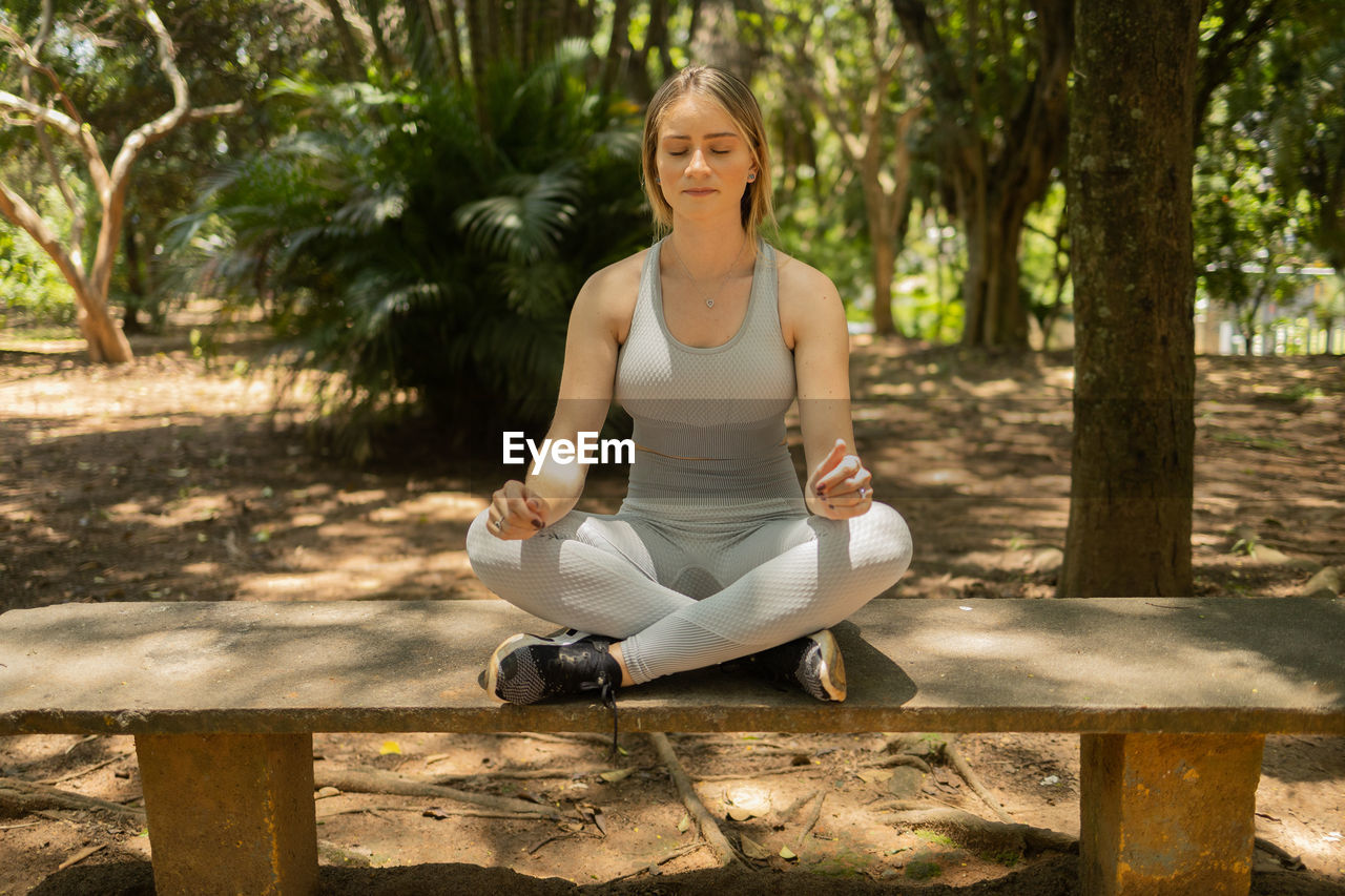 Young woman meditating. practice of yoga and meditation on a sunny day at a park, healthy, spiritual